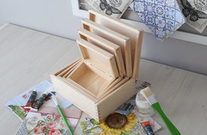 Set of 4 wooden nesting boxes presented on the desk surrounded with decoupage napkins glue paint brushes and paint tubes